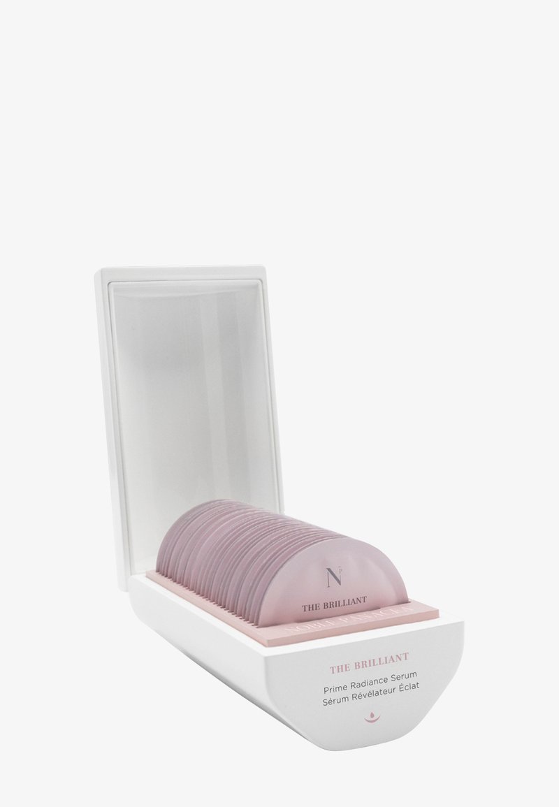 Conteneur rectangulaire blanc avec couvercle ouvert contenant plusieurs capsules incurvées roses à usage unique étiquetées The Brilliant.