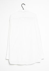 Bílá košile s dlouhými rukávy, límečkem, hladkým materiálem, jedním skladem vzadu a zakulaceným lemem. Visí na černém háčku na bílém pozadí.