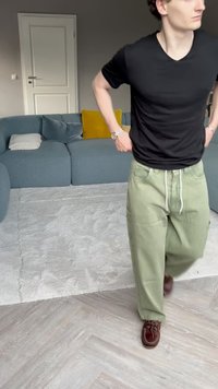 Calças cargo verdes com cintura elástica e bolsos laterais, combinadas com uma t-shirt preta de manga curta e sapatos castanhos.