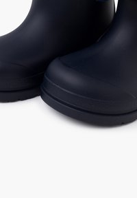 Stivali in gomma impermeabili blu navy con una texture liscia, punta leggermente rialzata e suola tassellata per una migliore trazione; progettati per l'uso all'aperto.