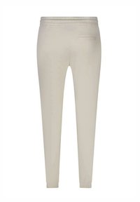 Jogging beige, élastiqué, avec une texture lisse, des jambes fuselées et une seule poche à l'arrière. Les poignets sont ajustés pour une finition confortable.