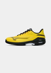 Baskets de sport jaunes avec des accents noirs, dotées d'un dessus texturé, d'un système de laçage et d'une semelle courbée pour un meilleur soutien. Logo affiché sur le côté.