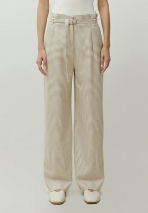 Beige gemusterte weite Hose mit einem taillierten Bund, die ein Hahnentrittmuster und eine glatte Stofftextur aufweist.
