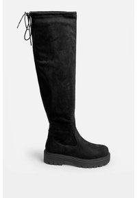 Svarta knähöga stövlar i mjuk mocka, med rund tå, texturerad yta och en kraftig gummisula med snörningsdetalj på toppen.