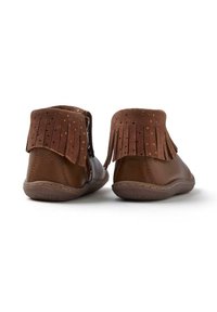 Las botas de cuero marrón hasta el tobillo presentan un cuello de ante con flecos y lunares. Las suelas son texturizadas para proporcionar agarre, y el diseño tiene un perfil casual.