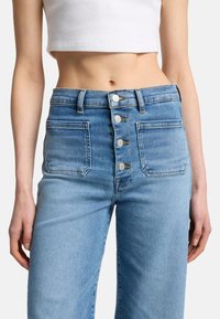 Lyseblå denimjeans med høy midje, med fem-knapps frontlukking, to sidelommer og en falmet tekstur.