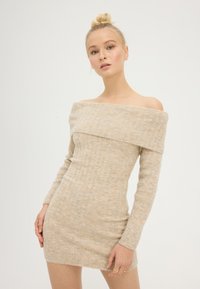 Abito a spalla scoperta, in tessuto a coste di colore beige chiaro, realizzato in un materiale morbido. Presenta maniche lunghe e una silhouette aderente.