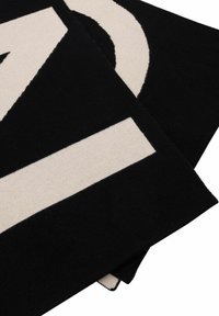 Woven rug w kolorze czarnym i kremowym z geometrycznymi wzorami, w tym wyraźnymi cyframi i paskami, o miękkiej teksturze i wyraźnych krawędziach.