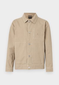 Beżowa kurtka z tkaniny, z kołnierzem z szpiczastym wycięciem, zapinana z przodu na guziki, z dużymi kieszeniami i subtelnym logo na piersi.