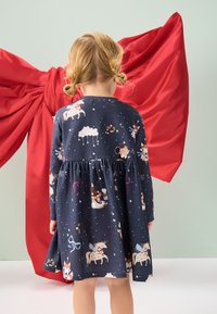 Dunkelblaues Kinderkleid mit langen Ärmeln, plissiertem Rock, verspielten Tiermotiven und weißen Sternmustern. Baumwollstoff, Rundhalsausschnitt.
