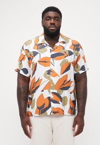 Camisa de manga corta con botones en blanco, con un patrón de hojas colorido en naranja, verde y azul marino; tejido ligero; corte relajado.