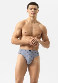 Shorts de bain pour hommes rayés en bleu et blanc, ornés de petits motifs floraux rouges. Le tissu est lisse avec un design ajusté et une taille élastique.