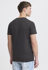 Camiseta de manga corta gris oscuro con cuello redondo clásico, textura suave y un diseño ajustado, combinada con jeans azul claro.