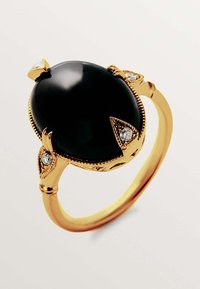 Anillo de piedra ovalada negra engastado en oro, con intrincados acentos dorados y tres pequeños diamantes dispuestos alrededor de la piedra.