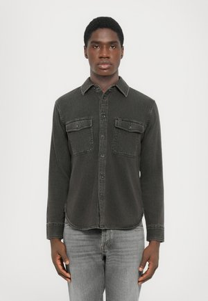Dark gray denim shirt with long sleeves, button-up front, and two chest pockets. Features a collar and a slightly curved hemline.