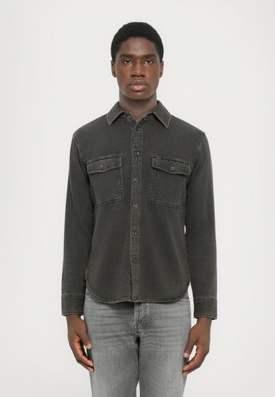 Dark gray denim shirt with long sleeves, button-up front, and two chest pockets. Features a collar and a slightly curved hemline.