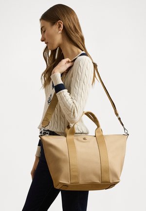Tan torba s dvostrukim ručkama i odvojivim remenom za rame. Glatka tkanina, strukturirani dizajn, naglašene pruge i suptilno brendiranje sprijeda.