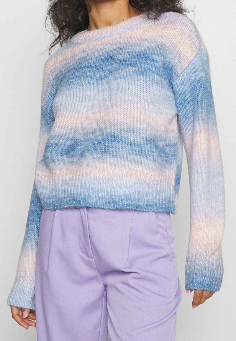 Pull en maille dégradé bleu et rose pastel avec manches longues et ourlet côtelé, doté d'une coupe décontractée et d'une texture douce.