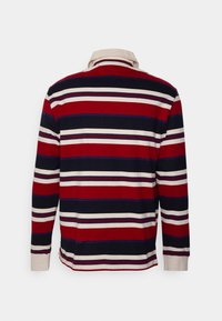 Polo de manga larga con rayas horizontales en rojo, azul marino y crema; presenta un cuello en crema en contraste y una suave textura de algodón.