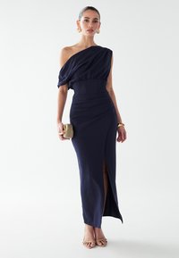 Vestido azul marino de un solo hombro con corpiño fruncido, cintura ajustada y una abertura lateral. Tela lisa con una silueta elegante y herrajes mínimos.