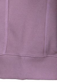 Vaaleanpunainen resorikangas, jossa on teksturoitu pinta. Saumoissa näkyvät tikit ja suora alareuna.