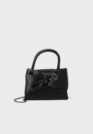 Black handbag made of smooth fabric, featuring a large satin bow, rounded handles, and a chain strap. Compact rectangular shape.