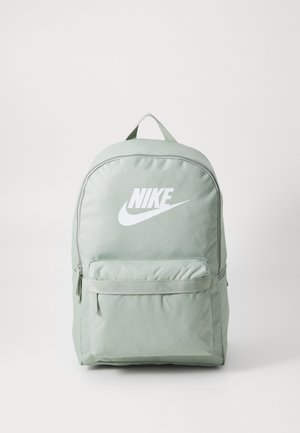Sac à dos Nike vert clair avec logo blanc, un compartiment principal zippé et une poche zippée à l'avant sur fond uni.