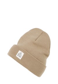 Cappello beanie in maglia beige con orlo piegato. Presenta un'etichetta quadrata con un design di montagna e cerchio. Texture morbida, design semplice.