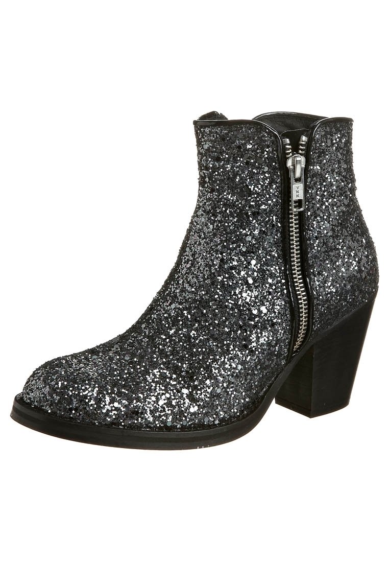 Bottine noire couverte de paillettes argentées avec fermeture éclair latérale et talon block, inclinée pour montrer le côté extérieur et la semelle.