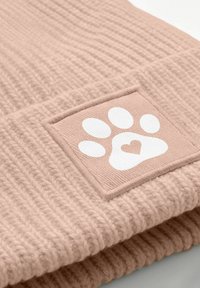 Soft pink knitted beanie with a white paw print and heart-shaped pad on a square patch sewn on the cuff.