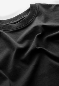 Sudadera negra de cuello redondo extendida, con cuello acanalado visible y pliegues suaves en la tela.