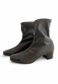 Botas de tobillo de cuero marrón con una textura suave, punta redondeada y una puntera brillante oscura. Presentan un tacón cuadrado bajo y detalles cosidos.