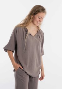Zachtgrijze, kort-sleeve top met een V-hals en decoratieve trekkoord. Gemaakt van lichte stof. Casual pasvorm, gecombineerd met bijpassende broek.