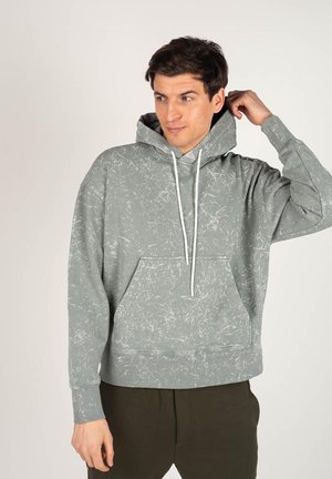 Lichtgrijze hoodie met wit abstract patroon, voorzak en trekkoordkap. Gemaakt van zacht materiaal met geribbelde manchetten.