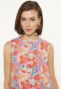 Top senza maniche floreale con scollatura a volant nei motivi rosa, rosso e blu, realizzato in un tessuto leggero e morbido, con un taglio rilassato.