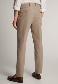 Beige linnenbroek met een slanke pasvorm, een vlakke voorkant en twee achterzakken. Draagt bruin loafers, toont een gestructureerde stof.