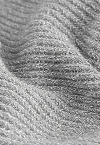 Tissu tricoté gris avec une texture douce, présentant des motifs tissés et des accents de fil argenté pour un effet scintillant.