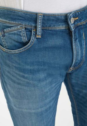 Blauwe spijkerbroek met een klassiek ontwerp met vijf zakken, met contrasterende gele stiksels en een gladde textuur. Knopen als sluiting bij de taille.