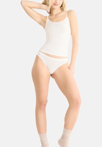 Witte camiset met dunne bandjes en bijpassende witte bikini slips, met een gladde, aansluitende textuur en een eenvoudig ontwerp. Kniehoge beige sokken inbegrepen.