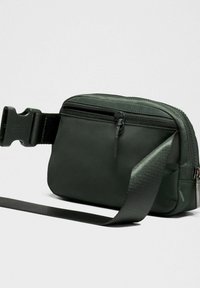 Zöld nejlon övtáska oldalsó cipzáros zsebbel, állítható pánttal és tartós fémalkatrészekkel. Simább textúrával és kompakt, téglalap alakú formával rendelkezik.