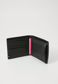 Portefeuille en cuir noir avec plusieurs emplacements pour cartes, un accent rayé rouge et blanc contrastant, et un compartiment à fermeture à pression.