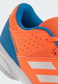 Oranžová a modrá sportovní bota s síťovinovým svrškem, perforovanými detaily a třemi bílými pruhy na boku, s gumovou podrážkou.