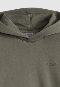 Χακί πράσινο φούτερ με απαλό ύφασμα, διαθέτει μεγάλη κουκούλα, ναυγαζωτά τελειώματα στα μανίκια  και λογότυπο κεντημένο στο στήθος. Στο εσωτερικό έχει επένδυση από φλις.