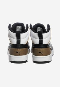 Sneakers alte con una toma bianca, dettagli neri e un contrafforte marrone. Materiali testurizzati e branding visibile sul retro.