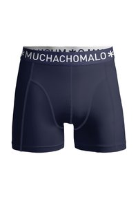 Tumsā zilā krāsā bokseru šorti, izgatavoti no elastīga auduma, ar baltu zīmola jostu, uz kuras treknā burtā ir rakstīts "MUCHACHOMALO".