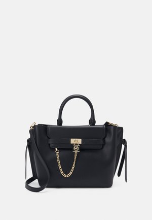 Borsa a tracolla in pelle nera con hardware dorato, forma rettangolare, due manici superiori e una tracolla rimovibile. Presenta un dettaglio a catena e una chiusura a morsetto.