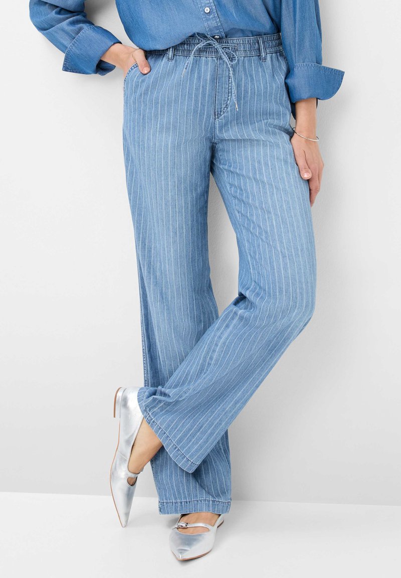 Pantaloni a gamba larga blu chiaro con strisce verticali bianche, realizzati in denim. Vita elastica con cordoncino; da abbinare a ballerine argento a punta.