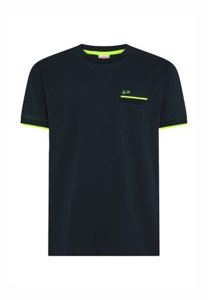 T-shirt noir à manches courtes avec bordure vert néon sur le col, les extrémités des manches et le haut de la poche, orné de petits symboles géométriques au-dessus de la poche.