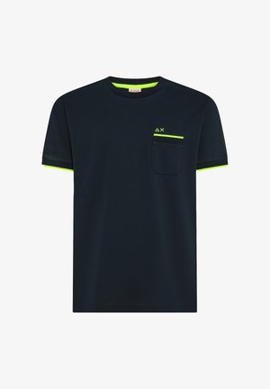 Schwarzes T-Shirt mit kurzen Ärmeln und neon-grünem Besatz am Kragen, an den Ärmelsäumen und am oberen Rand der Tasche, mit kleinen geometrischen Symbolen über der Tasche.