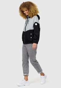 Windbreaker jacket in black and grey, featuring a hood, zip closure, elastic cuffs, and front pockets with white accent buttons.